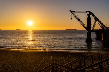 Gün batımında arkasında bir gemi olan Vergara iskelesi vinci.