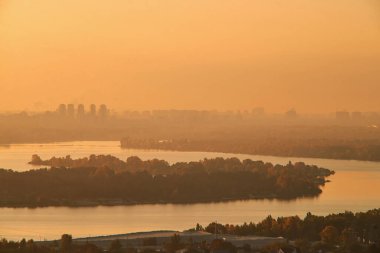 Sabahın erken saatlerinde nehrin iki yakasında. Ukrayna 'daki Kiev şehrinin gün doğumu manzarası. Sıcak ışık ve solgunluk..