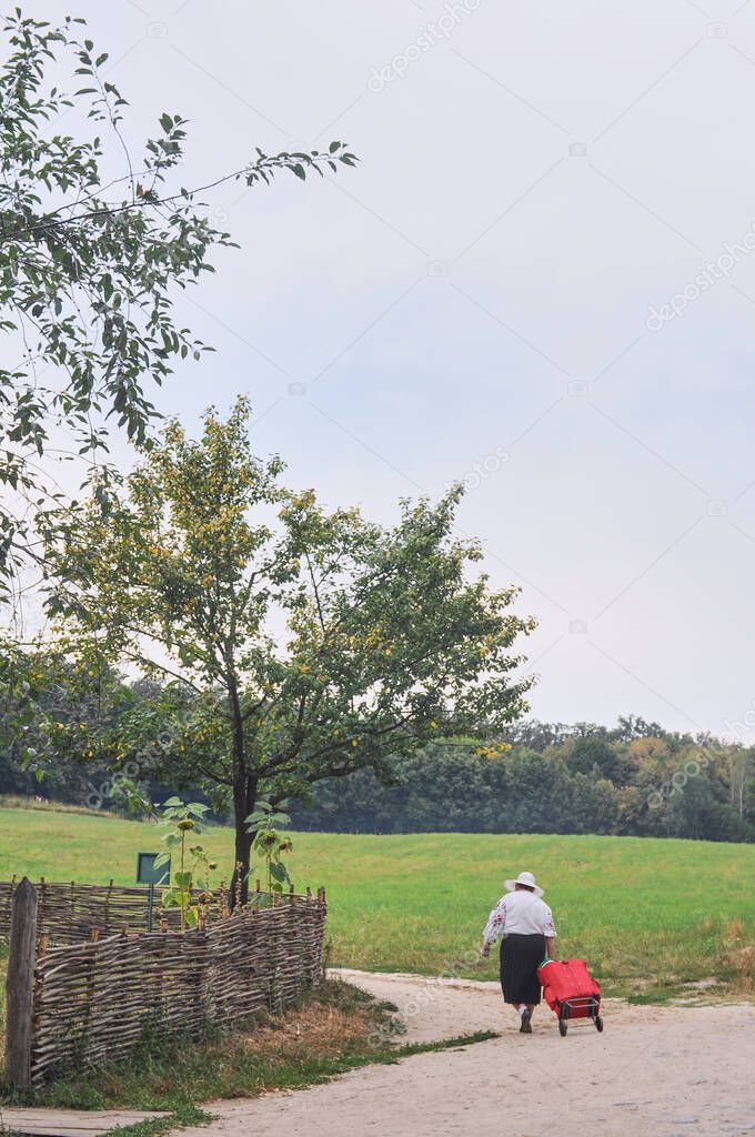 rear view of old woman walking on rural road