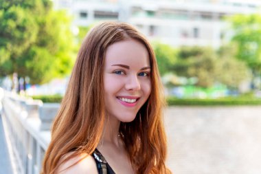 Açık tenli kızıl kız güneşli bir günde gülümsüyor.