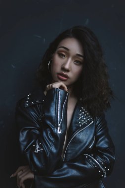 Parlak makyajlı ve kısa siyah saçlı Asyalı kız duvarın yanında kalıyor.