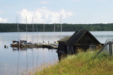 Göldeki eski kır evi ve arka planda yelkenli.