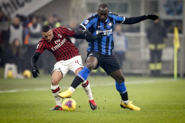 MILAN, ITALY - FEBRUARY 17, 2020: Ismael Bennacer, Milan, and Romelu Lukaku, Inter, vie for the ball. clipart