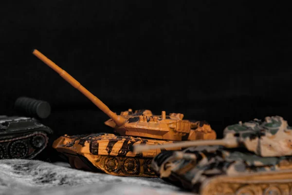 Toy tanks in macro. Left turn . Background of black color