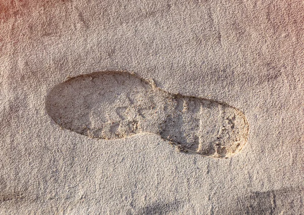 Footprint from a shoe on white sand.
