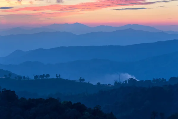 Camada de montanhas na névoa ao pôr do sol tempo com céu ardente , Fotos De Bancos De Imagens Sem Royalties