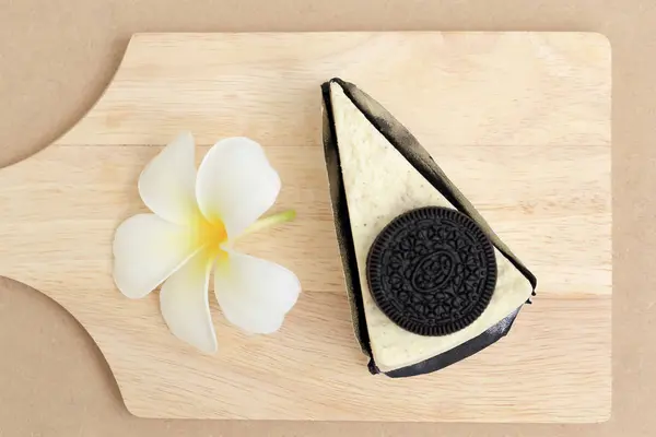 Pedaços de biscoito Cheesecake e flor branca em placa de madeira . — Fotografia de Stock