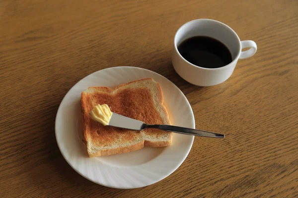 Petit déjeuner, assiette de pain grillé au beurre et tasse de café noir . — Photo