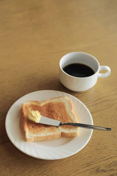 Desayuno, plato de tostadas con mantequilla y taza de café negro . —  Fotos de Stock