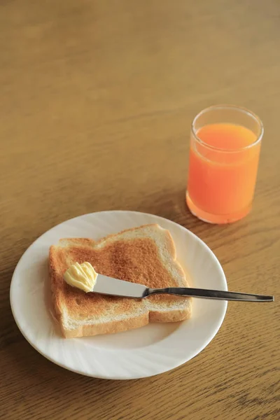 Desayuno, plato de tostadas con mantequilla y zumo de naranja . —  Fotos de Stock
