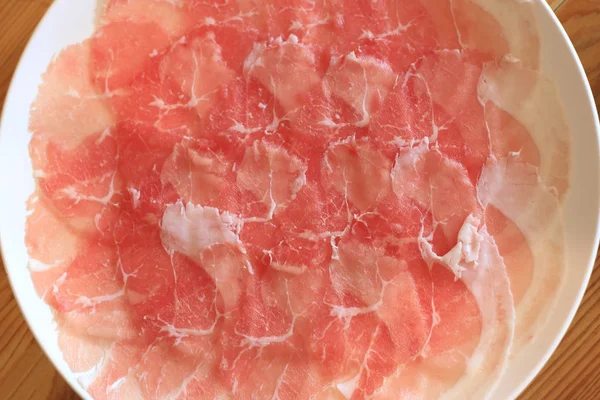 Van varkensvlees gesneden in witte schotel voor shabushabu, Japanse recept (bovenaanzicht). — Stockfoto