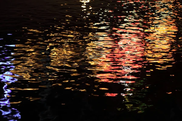 Fondo abstracto de reflexión de la luz colorida en la ola de agua en la noche . —  Fotos de Stock