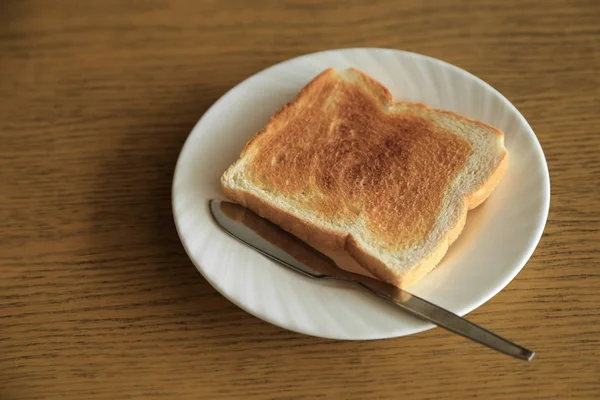 Bir tost ile gümüş tereyağı bıçağı ahşap masa arka plaka — Stok fotoğraf