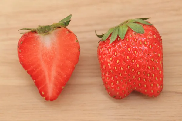 Frische Erdbeere voller Körper und die Hälfte auf Holzgrund. — Stockfoto