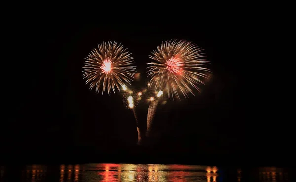 Festligt firande ljus fyrverkeri på natten över vattnet, nyår semester bakgrund. — Stockfoto