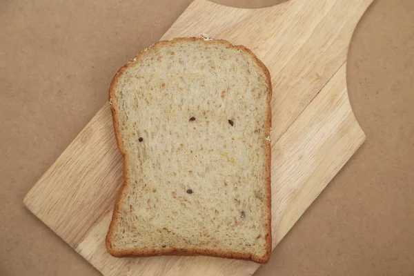 Ψωμί ολικής άλεσης στο ξύλινο πιάτο και καφέ υφή φόντου. — Φωτογραφία Αρχείου