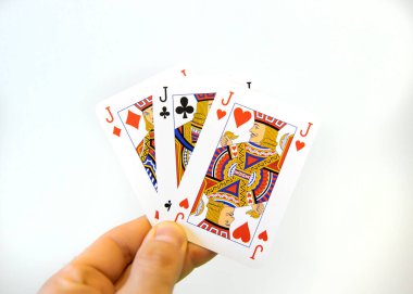 Beyaz bir arka planda elinde poker kartlarından oluşan üçlü bir el..