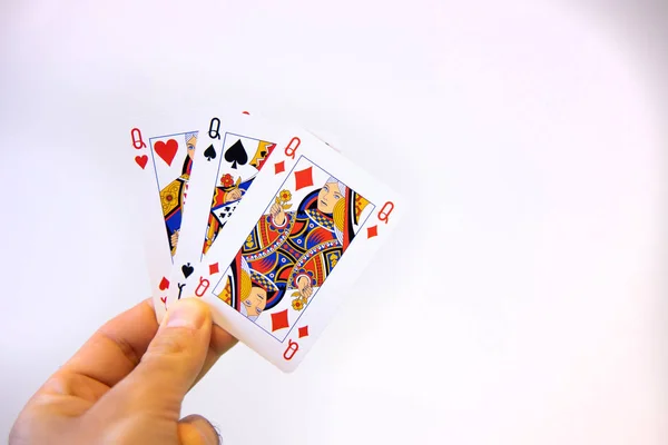Hand holding a trio of queen cards of poker over a white background.