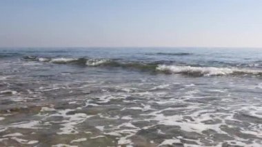 Temiz şeffaf suyu ve rahatlatıcı dalgaları olan bir kumsal manzarası