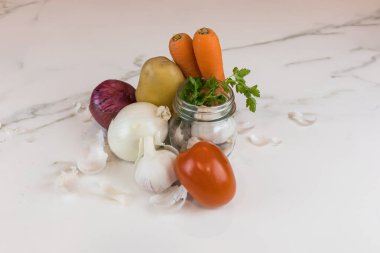 İçinde havuç, patates, soğan, sarımsak, maydanoz ve bir domates bulunan çiğ organik sebze kompozisyonu..