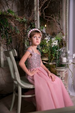 Pembe elbiseli küçük kız ve şapka sihirli çiçeklerin arasında oturuyor.