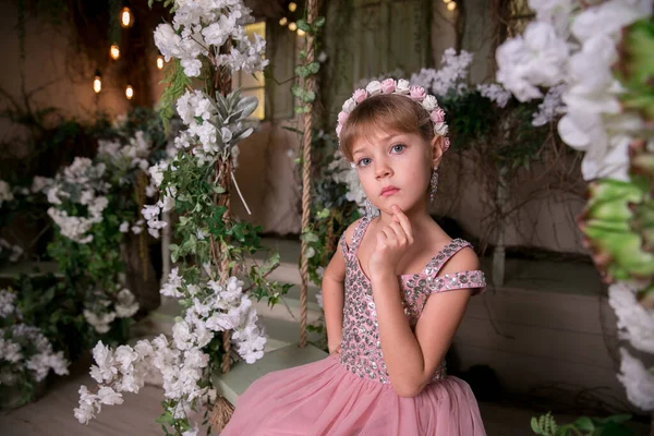 穿着粉色衣服头戴粉色帽子的小女孩坐在神奇的花朵中 — 图库照片