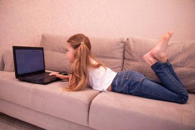 Evde dizüstü bilgisayarla çalışan mutlu küçük bir kız.