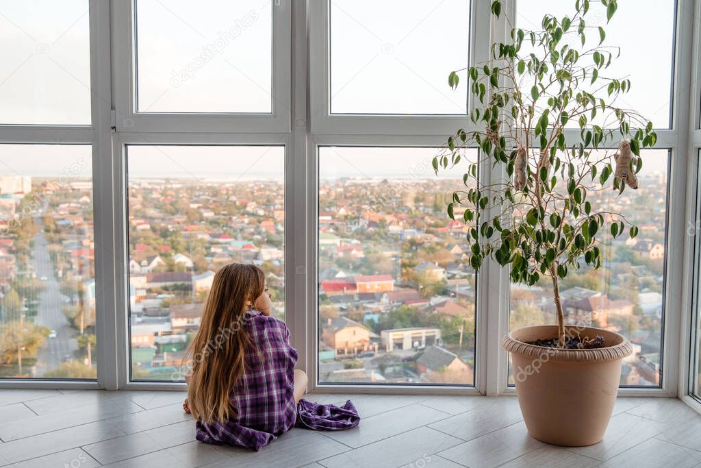 Cat and girl looking out of the window. Child with pet windows looks at the city. self-isolation