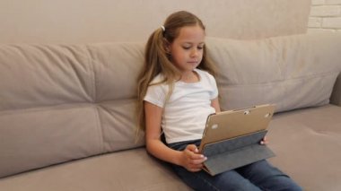 Evde dizüstü bilgisayarla çalışan mutlu küçük bir kız.