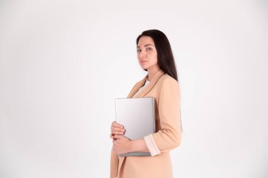 Fotokopi alanı olan gri arka planda başarılı bir iş kadını. Dizüstü bilgisayarlı bej takım elbiseli yönetmen.