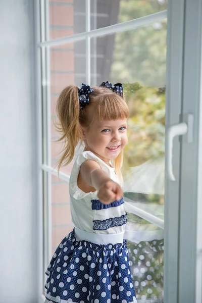 A little sweet girl by the window. happy childhood