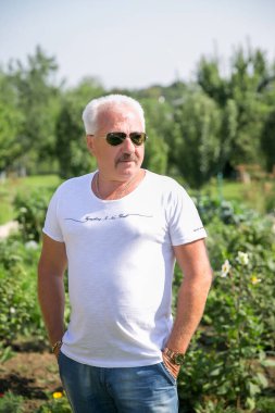 Emekli adam gözlükleri tatil bahçesinde rahatlar.