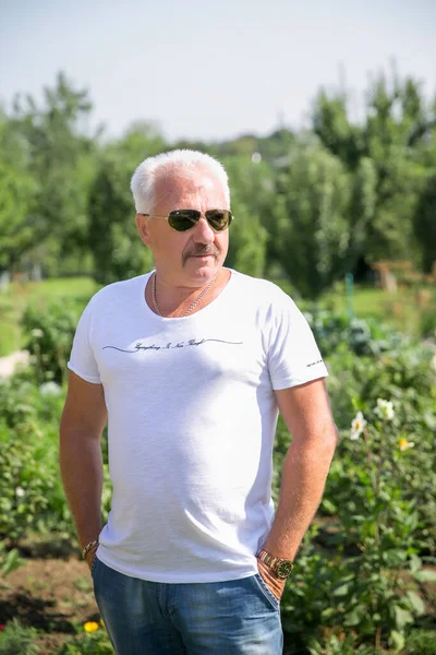 Emekli adam gözlükleri tatil bahçesinde rahatlar.