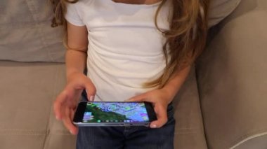 Evde bir koltukta oturup cep telefonuna dokunan sıradan bir bebek.