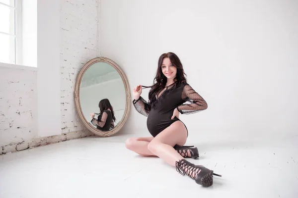 鏡の前で黒人ボディの魅力的な妊婦の写真 白い背景 — ストック写真