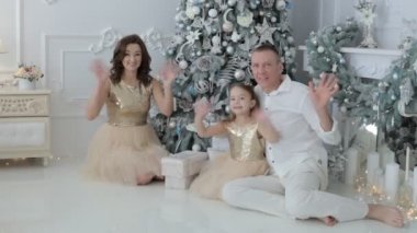 Aile neşeyle tebrik Noel ağacının yanında tebrik ellerini sallayarak.