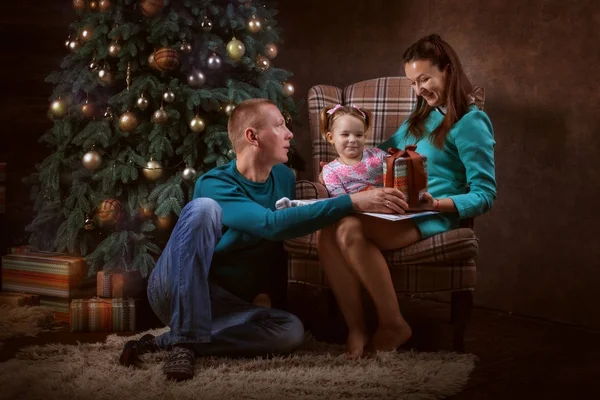 Vader, moeder en hun dochter in de buurt van een kerstboom — Stockfoto