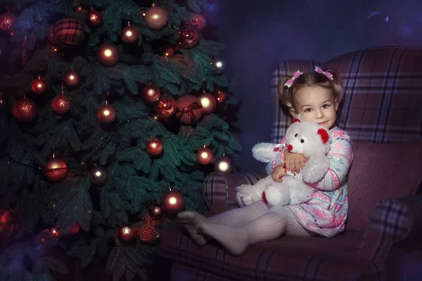 Chica se sienta cerca de un árbol de Navidad —  Fotos de Stock