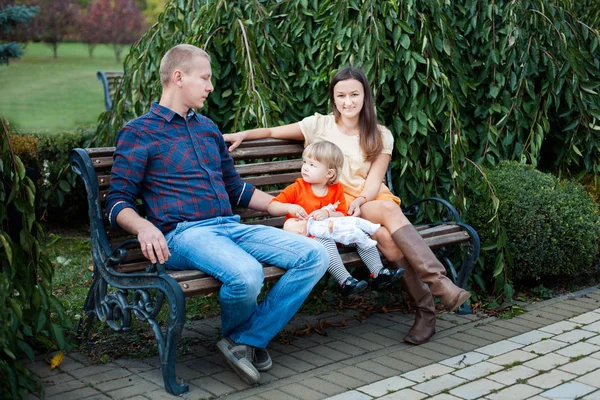 Famille assise sur un banc dans le parc . — Photo