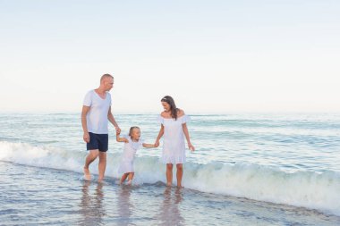 Kumsalda yürüyen genç ailesi.