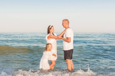 Baba, anne ve kızı plajda duruyoruz.