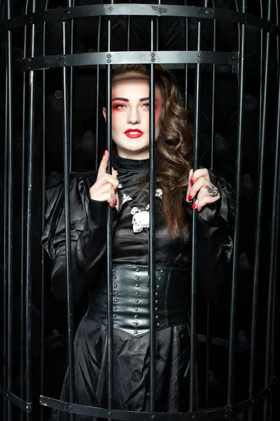 Frau steht in einem schwarzen Käfig. — Stockfoto