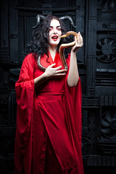 Porträt einer Frau mit Hörnern in einem roten Kleid. — Stockfoto