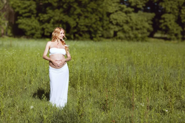 Mulher grávida bonita de pé na grama . — Fotografia de Stock