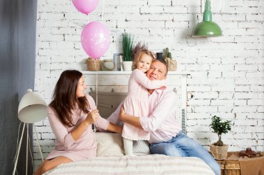 Genç aile yatağın üstüne oturuyor.