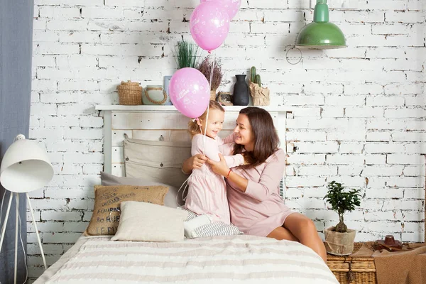 Moeder en dochter zitten op het bed. — Stockfoto