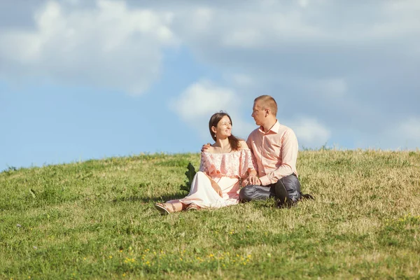Jovem casal amoroso sentado em uma colina . — Fotografia de Stock