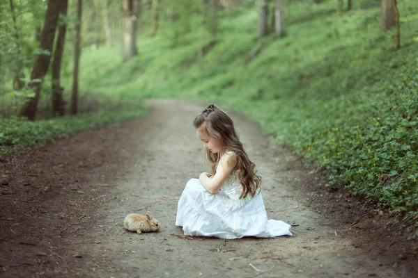 Meisje met kleine konijn in het bos. — Stockfoto