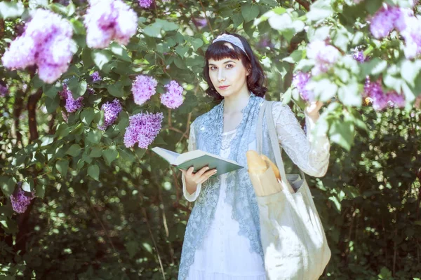 Piękna młoda kobieta stoi w pobliżu liliowy. — Zdjęcie stockowe