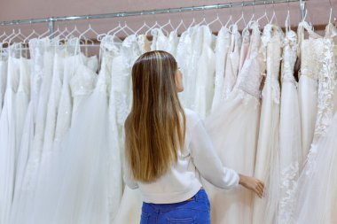 Düğün salonundaki kadın gelinliklere bakar..